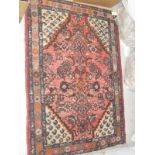 A pink ground Persian rug with all over floral decoration with cream ground spandrels decorated