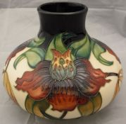 A Moorcroft squat baluster shaped vase with floral decoration on a cream ground bearing initials "S