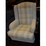 A modern armchair in blue and cream checked upholstery raised on ringed and turned legs to brass