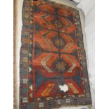 A red ground Kazak rug, the central field with three hooked medallions in blues, yellows,
