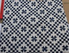 A 19th Century quilt of blue and white checkerboard and flower head design on a plain white backing