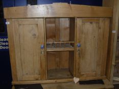 A pine wall hanging cupboard with two open recesses flanked by panelled cupboard doors to plinth