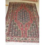 A red ground Persian rug with central shaped medallion on a red field with black spandrels and