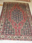 A red ground Persian rug with central shaped medallion on a red field with black spandrels and