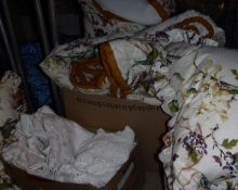 A box containing two cotton lined bed throws in floral decorated fabric,