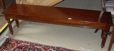 A long mahogany window seat with cleated end supports to four turned and reeded legs