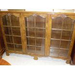 An early to mid 20th Century walnut display cabinet with three glazed and barred door enclosing