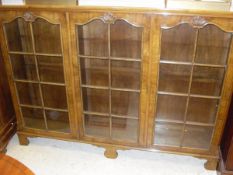 An early to mid 20th Century walnut display cabinet with three glazed and barred door enclosing