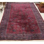 A Persian rug, the central panel with repeating floral sprays on a puce ground,