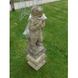 A composite stone figure statue of a boy in a coat on a baluster shaped base