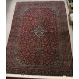 A red ground Kashan carpet with stepped central medallion in a blue,