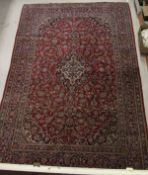 A red ground Kashan carpet with stepped central medallion in a blue,