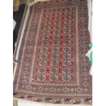 A Bokhara rug on a red ground with thirty-nine elephant foot ghouls on a stepped foliate decorated