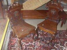 A pair of 19th Century mahogany hall chairs with carved and moulded shield shaped backs,
