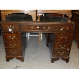 A reproduction kneehole desk with leather top above two banks of three drawers
