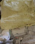 A box containing assorted vintage table linens to include a pale yellow table cloth and matching