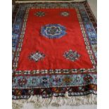 A 20th Century Turkish rug, the central panel set with geometric medallions on a bright red ground,