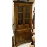 An oak corner display cupboard with dentil cornice above two astragal glazed doors enclosing