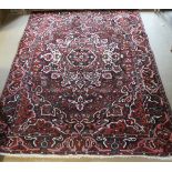 A Persian burgundy ground carpet with central stepped floral medallion in shades of salmon, black,