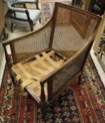 A 19th Century bergere library chair on turned and reeded front legs to brass castors