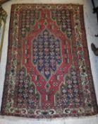 A Persian rug, the central shaped medallion on a red ground with black spandrels,