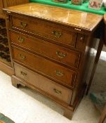 A small walnut and feather banded bachelor's chest of four drawers with fold-out top above the four