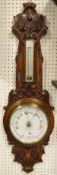 A circa 1900 carved oak framed barometer/thermometer with scrolling floral decoration in the Art