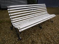 A white painted slatted garden bench with three wrought iron supports