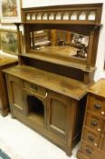 A circa 1900 oak Arts and Crafts style sideboard with a mirrored back supported by turned legs on a