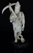 A Japanese Meiji Period carved ivory okimono as a fisherman with anchor over his shoulder and
