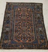 A Caucasian rug, the repeating blue motifs on a rust ground, within a stepped border,