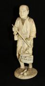 A Japanese Meiji Period carved ivory okimono as a market trader with scales and basket of gourds,