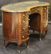 A Victorian mahogany kidney-shaped desk with quarter brass gallery and green leather tooled inset