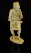A Japanese Meiji Period carved ivory okimono as a woodsman, an axe in one hand,