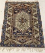 A Caucasian rug, the central diamond-shaped medallion on a cream ground with blue spandrels,