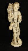 A Japanese Meiji Period carved ivory okimono as a woodsman with axe and basket of wood over his