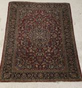 A Kashan rug, the black ground central medallion and black ground spandrels on a raspberry ground,