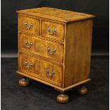 An oyster walnut and inlaid chest of two short over two long drawers to turned feet, 66.