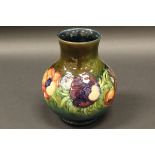 A William Moorcroft baluster shaped vase with floral decoration on a blue green ground,