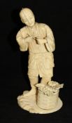 A Japanese Meiji Period carved ivory okimono as a man with pipe, a basket of vegetables at his feet,