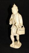 A Japanese Meiji Period carved ivory okimono as a market trader with basket of vegetables,