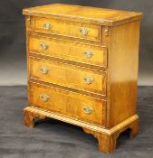 A walnut and banded bachelor's chest with fold-out top above four graduated drawers,