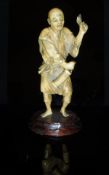 A Japanese Meiji Period carved ivory okimono as a man with lantern in one hand,
