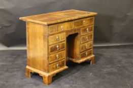 A walnut and feather-banded kneehole desk in the 18th Century manner,