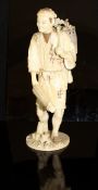 A Japanese Meiji Period carved ivory okimono as a man with parasol in one hand,