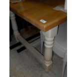 A modern stained beech farmhouse style kitchen table on cream painted base with centre stretcher