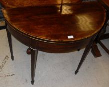 A Regency mahogany and rosewood cross-banded fold-over tea table of demi-lune form