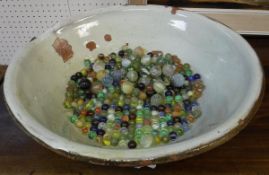 A glazed terracotta bowl containing vintage and later marbles