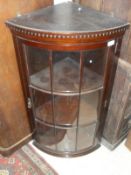 A mahogany hanging corner cabinet with glazed and barred door enclosing two shelves