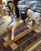 A 20th Century dapple painted rocking horse on pine base with extra leather saddle by J Highet